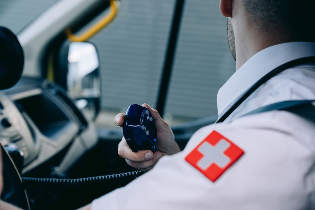 about-01 A paramedic in uniform using a radio in an ambulance, demonstrating emergency preparedness.